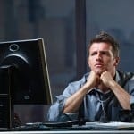 Determined businessman concentrating hard on difficult computer task working late in office looking worried.?